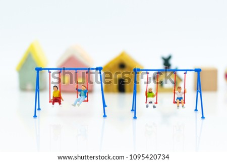 Miniature people : children playing swing with family. Image use for happy family day concept.