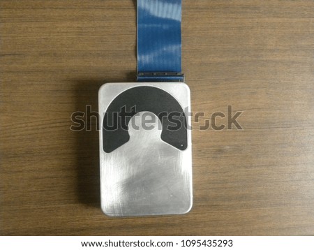 Old aluminium hard disk drive on wood background connected with blue color cable ribbon connector