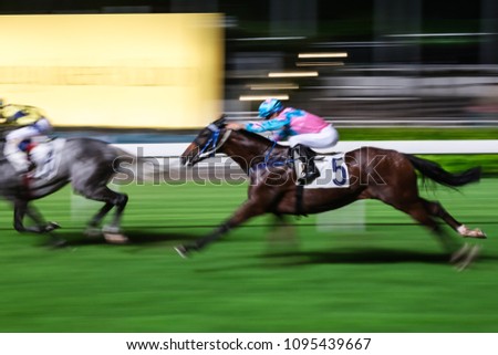 Racehorses ridden by jockeys running fast during the race at racetrack. Striving to victory. Hong Kong Happy Valley race course. Motion blur. Royalty-Free Stock Photo #1095439667