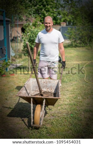 man pushing wheelbarrow. Young man pushing a wheelbarrow on the farm.. vignetting