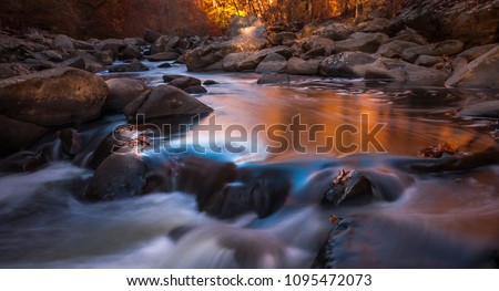 Rock Creek Pool - This long exposure image of the pool inside Rock Creek Park captures the autumn colors of orange and yellow.  It is located between Silver Spring MD and Washington DC Royalty-Free Stock Photo #1095472073