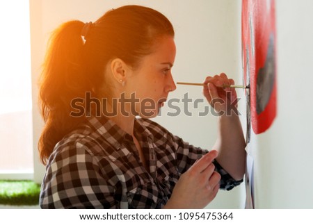 Young woman painter and mother boy draws for a child on a white wall a beautiful red car in a light children's room