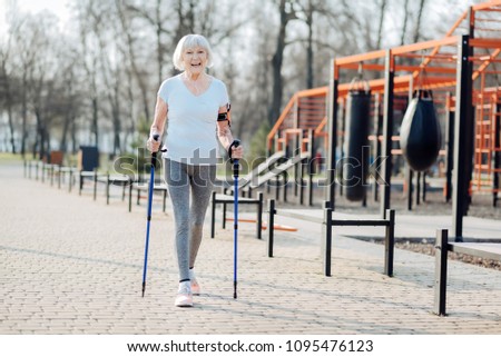 I like sport. Inspired blond woman smiling and walking with the help of crutches