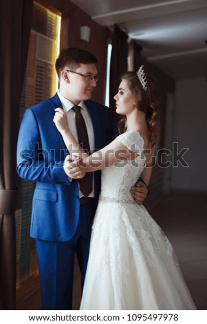 Stylish Groom wearing glasses and a blue suit and a bride in a white long dress with a wedding dress in hair style. Married