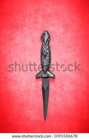 Black Wiccan or witchcraft dagger on a textured red background