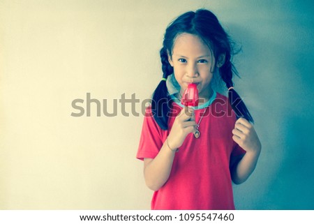 Little girl wearing a red shirt .Eats red ice cream.On the wall.With coloring on program.