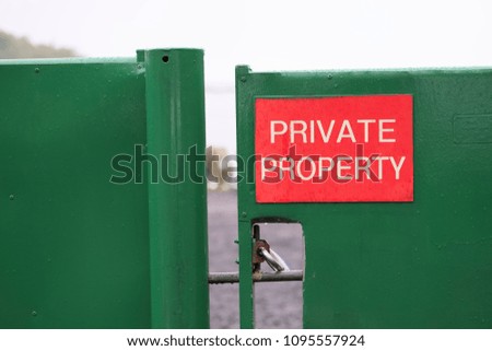 Private property sign red on green closed shut gate at Loch Lomond rural estate Scotland