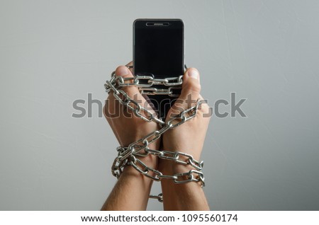 Mobile phone chained to the hands of a man, telephone dependence Royalty-Free Stock Photo #1095560174