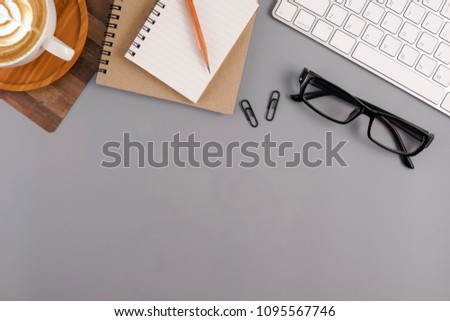 Flat lay, top view office table desk. Workspace with blank note book, keyboard, office supplies and coffee cup on grey color background.