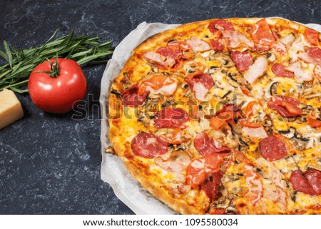 Fresh homemade pizza with pepperoni, ham, cheese and tomato sauce on rustic stone background.