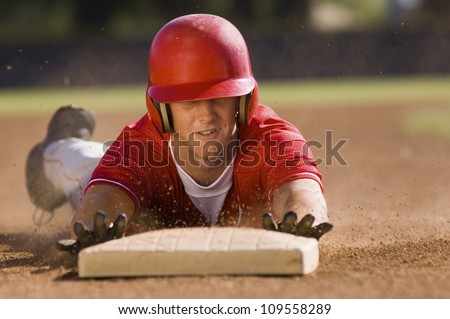 Young baseball player sliding towards second base on field