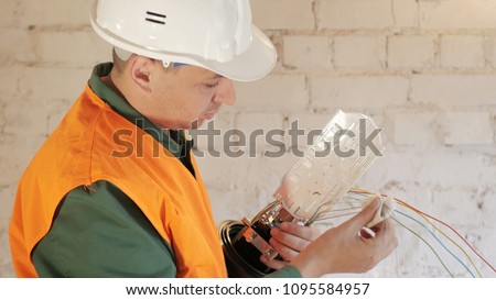 A network engineer in a server room with an optical cable. Royalty-Free Stock Photo #1095584957