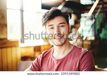 Portrait of handsome Hispanic man with stubble beard looking at camera and smiling