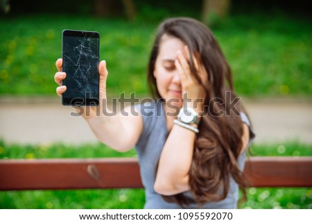young sad adult woman showing cracked phone