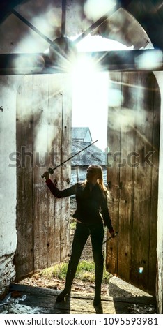 blond woman warrior with a sword stand on old, retro, vintage, aged opened door background. medieval female elf with sword looking inside church