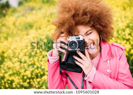 Happy mixed race woman in a beautiful flower field holding a vintage camera
