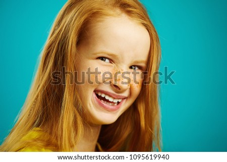 close-up shot, sincere laughter of cute baby girl with red hair and freckles on blue isolated. Concept of happiness child's.