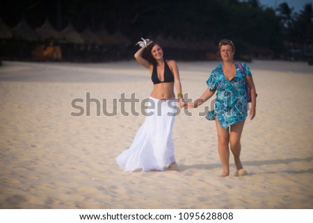 mom and daughter walk on the beach in the summer