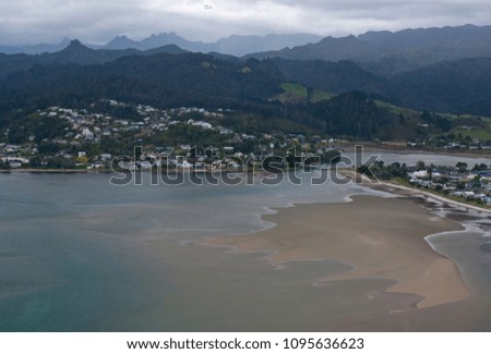 A town by the sea in a bay with hills in the background in Coromandel in New Zealand
