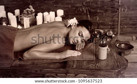 Massage of woman in spa salon. Girl on candles background in herbal steam room. Luxary interior in oriental therapy salon. Female have relax after sport. Toning brown sepia.