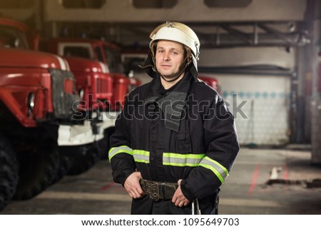 Fireman (firefighter) in action standing  near a firetruck. Emergency safety. Protection, rescue from danger.