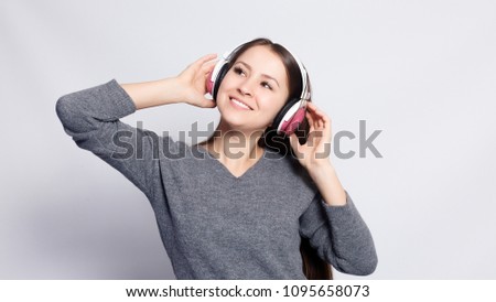 People, leisure and technology concept - happy woman or teenage girl in headphones listening to music from smartphone and dancing