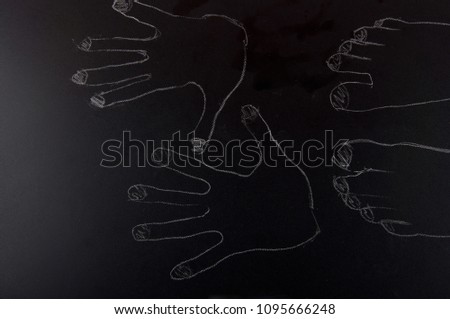 Chalk outline of human feet and palms on black background