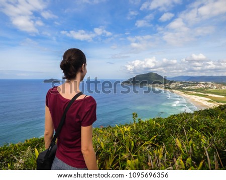 Woman looking at Santinho beach from a viewpoint - Florianopolis, Brazil