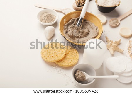 Preparing cosmetic mud mask in ceramic bowl on white background. Closeup texture of facial clay emulsion. Natural cosmetics for home or salon spa treatment Royalty-Free Stock Photo #1095699428