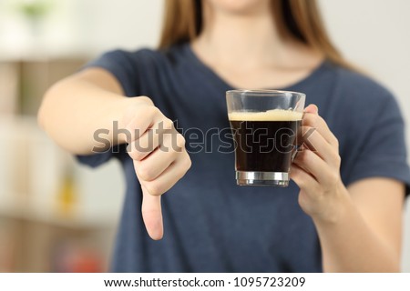 Front view close up of a woman hands holding a coffee cup with thumbs down at home Royalty-Free Stock Photo #1095723209