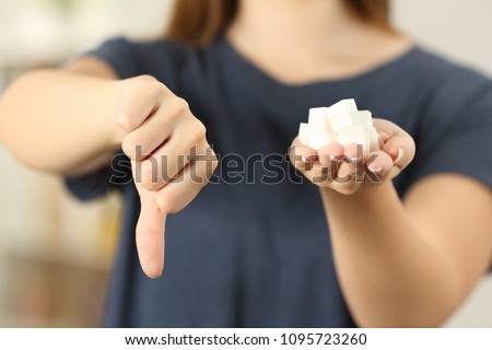 Front view close up of a woman hand holding sugar cubes with thumbs down at home Royalty-Free Stock Photo #1095723260