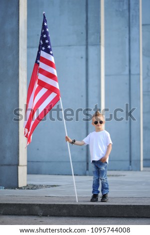 Happy cute boy  waving American flag outside, wearing  white shirt and jeans. Child celebrating 4th july - Independence Day of USA. symbol of freedom and independence.