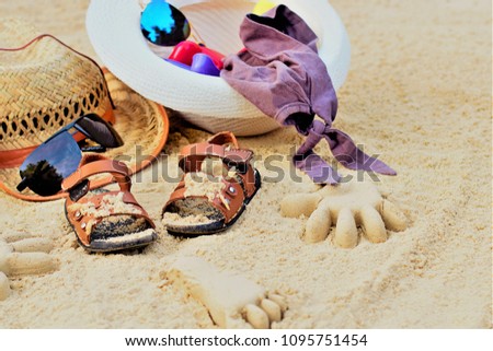 Sand on the beach or in the sandbox and footprints in the sand. Form for sand and children's shoes nearby. Nearby accessories to protect the sun rays of parents. Background image for copy space.