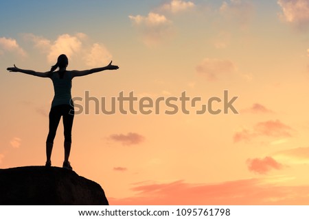Young woman silhouette against sunset with arms up in sky feeling free and happy. Freedom, and joy concept.   Royalty-Free Stock Photo #1095761798