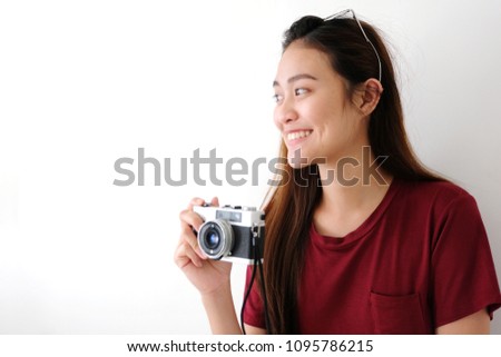 Young asian woman holding vintage camera with smiling face standing over white wall background with copy space, people positive expression, travel summer holiday vacation concept