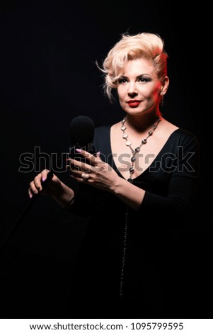 beautiful girl sings into a microphone on black background