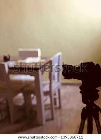 Professional camera on a stand shooting a table and chairs.