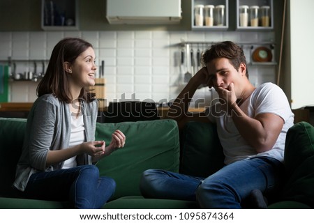 Young husband yawning getting bored listening to excited wife talking for a long time, tired boyfriend not interested in girlfriend gossiping sitting on couch at home, boring conversation concept Royalty-Free Stock Photo #1095874364