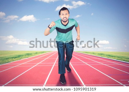 Picture of African man wearing sportswear while jogging on the running track