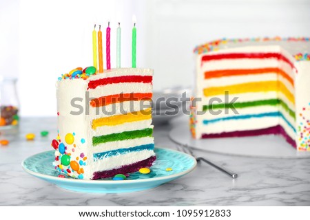 Delicious rainbow cake with candles for party on table