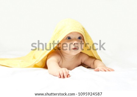 Charming, cute, happy baby girl with blue eyes in a yellow towel on a white background.
