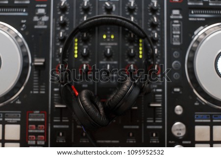 Professional headphones lie on the audio DJ controller. Top view