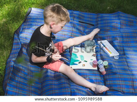 Cute little boy painting picture, outdoors