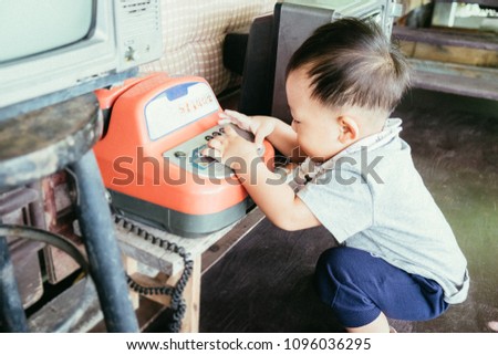Cute little asian baby boy relaxing and playing antique telephone in summer day at cafe.  Film grain style effect picture