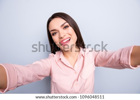 Self portrait of pretty charming cheerful cool crazy funny woman shooting selfie on front camera with two hands isolated on grey background, gesturing tongue out