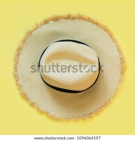 Straw beach sun-hat on yellow. Female outfit for heat. Square image. Minimal summer. Trendy color Illuminating of the 2021 year.