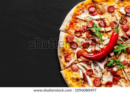Meat  Pizza with sausage,  mozzarella cheese and tomato on black stone background with copy space. Pizza delivery.