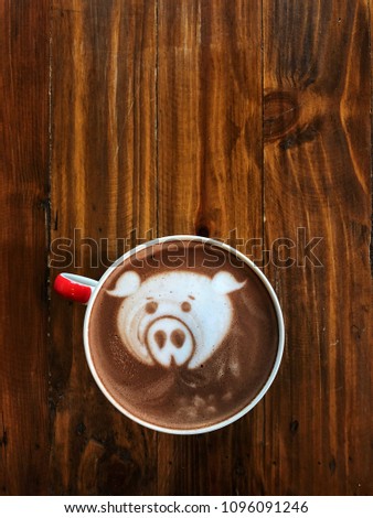 Cute pig face latte art coffee in white cup on wooden table ; cute latte art in your cup , love eat love coffee