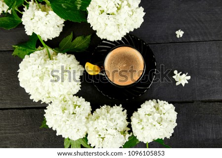 Cup of coffee with bouquet flower hydrangea on black wooden background. Good morning. Flat lay. Top view.