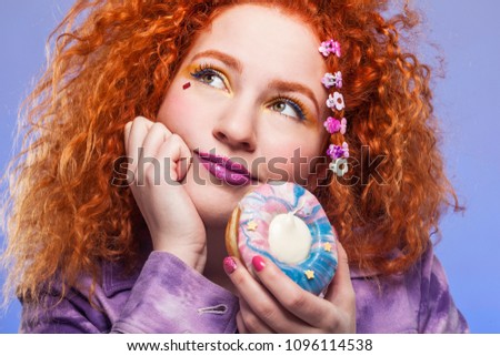 Ginger girl holding colorful donut